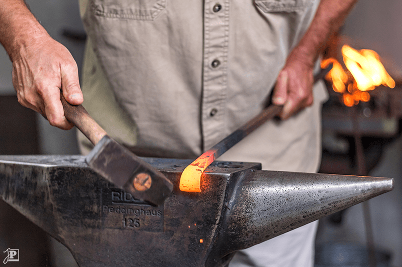 Blacksmith hitting steel on an anvil with a hammer